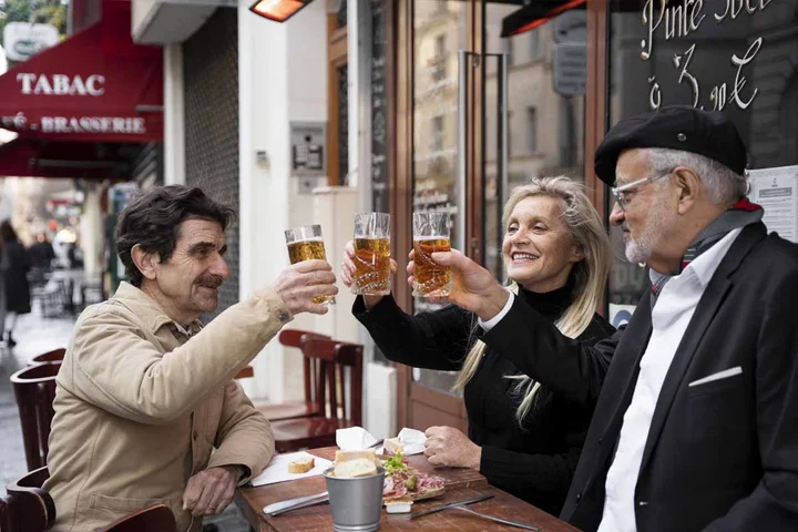amigos franceses brindando con cerveza en una terraza